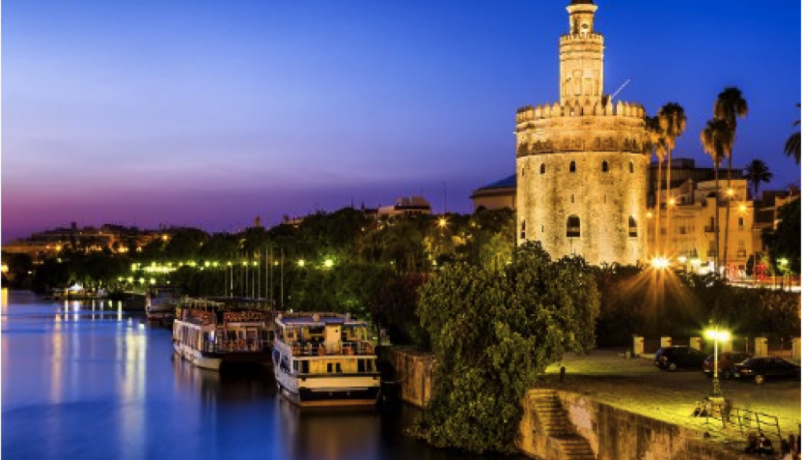 Moving to Sevilla - Panoramic view of Sevilla at night with the Torre del Oro (Gold Tower)